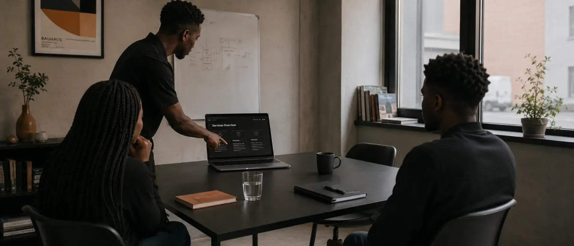 Project lead presenting a services overview to a seated client and teammate during a focused working session